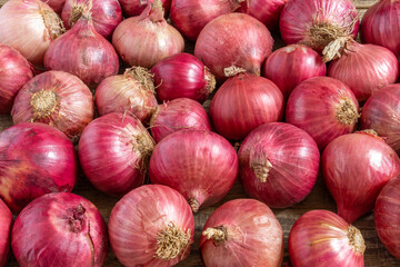 Red onions on shabby wooden board.