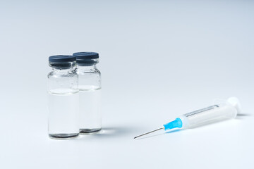 Close up glass vial with flu vaccine and syringe with needle. The concept of vaccination or preventive treatment of injection diseases.