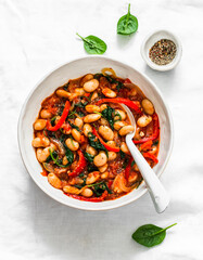 Vegetarian greek style tomato sauce, spinach, paprika, beans stew on a light background, top view