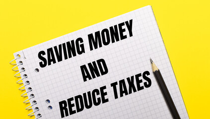 White notebook with inscription SAVING MONEY AND REDUCE TAXES written in black pencil on a bright yellow background.