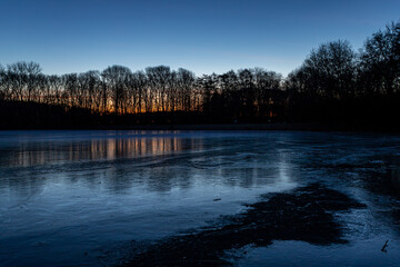 frozen ice surface of Decksteiner Weiher lake in Cologne at sunrise