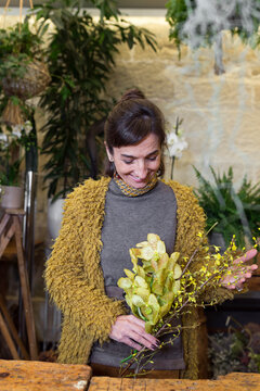 Portrait of cheerful woman holding yellow flowers at slower shop