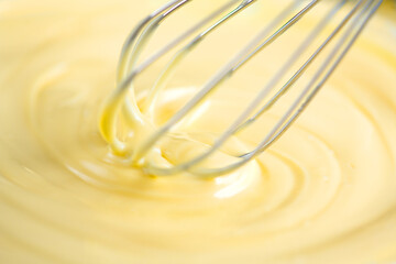 White Chocolate mixing with a whisk. Pouring melted liquid premium milk white chocolate. Close up of molten liquid hot chocolate swirl. Confectionery. Confectioner prepares dessert, icing 