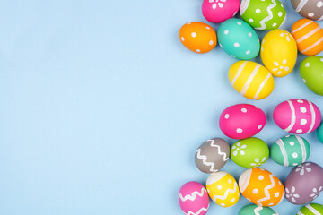 Colorful Easter Egg side border over a pastel blue paper background. Copy space.