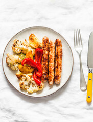Chicken sausage and roasted vegetables on a light background, top view