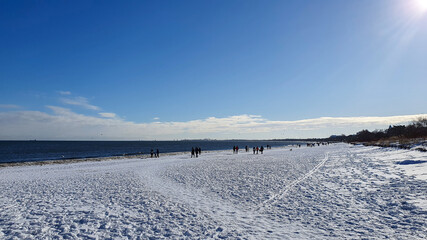 People are walking on a snow-covered beach in Sopot on a beautiful sunny day, Poland