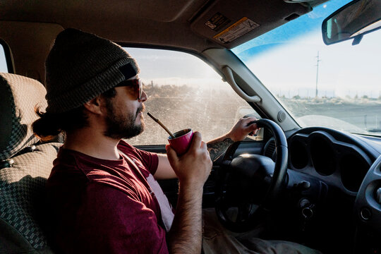 A man drinks Mate while drving along Ruta 40 in Argentina.