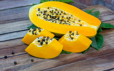 Fresh slices of papaya fruit with green leaves on wooden background.Tropical fruit.