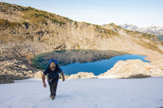 A solo mountaineer ascends a snow patch en to route Douglas Peak, B.C.