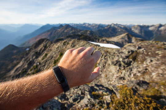 Trail runner checks his fitness watch while on a mountain ridge.