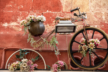 Fototapeta na wymiar an old bicycle as a flowerbed hanging on the wall of a building in Gravina in Puglia . Italy