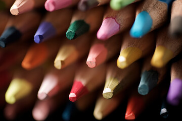 Watercolor pencils lined up on a black table.
