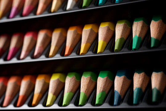 Watercolor pencils lined up in a black plastic box.