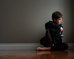 Preteen boy sitting on floor with video game controller in hand.