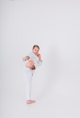 boy in a white kimono with a blue belt makes a kick on a white background with space for text. Martial arts for children