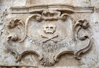 A bas-relief with a skull and a Latin inscription from the facade of the Church of Purgatorio in Gravina in Puglia. Italy