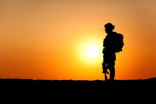 Modern army infantry soldier silhouette on sunset background