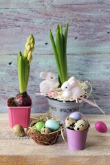 Easter eggs, hyacinth in a pot with toy hares on a wooden table, spring, festive home interior, congratulations, postcard
