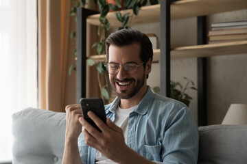 Great news. Overjoyed excited man in glasses read email from cell screen get awaited job offer...