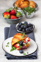 Croissant sandwich with cheese , arugula and berries.