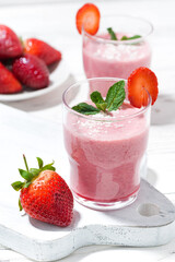 glasses of refreshing strawberry milkshake on white table