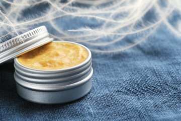 Jar of natural cosmetic product on blue linen fabric