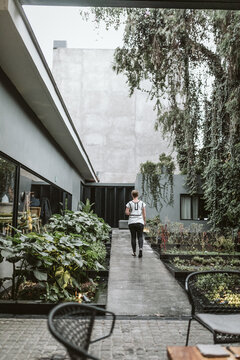 woman walks along cement walkway through a garden at Pujol in cdmx