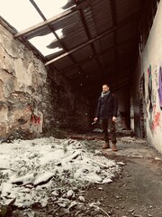  winter portrait of a man holding his camera and wears jacket scarf and camera in a abandoned location 