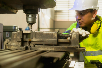 professional asian male engineer specialist worker wearing uniform hand control drilling machine manufacturing factory emgoneer concept