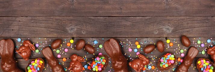 Easter candy and chocolate bunnies and eggs. Bottom border against a rustic dark wood banner...