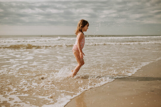 young girl wearing bathing suit splashing in the ocean