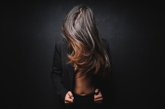 Young beautiful woman shaking hair in front of black background
