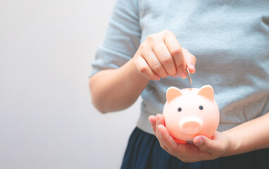 business woman hold piggy bank and putting coin with concrete wall for financial and saving money...