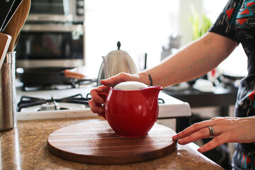 red teapot and hands in a kitchen in the day