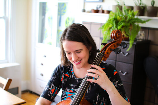 a woman happily plays her cello