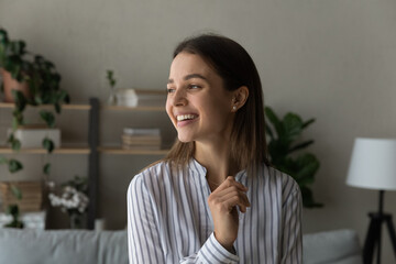 Fototapeta na wymiar Full of hopes and dreams. Head shot of pretty young woman stand at home look aside with dreamy smile imagine visualize good future. Serene cheerful teenage female loving life enjoy every beautiful day