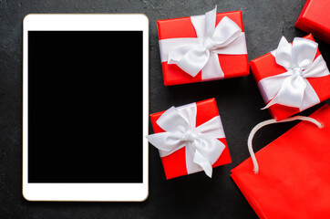 Red gift boxes and a tablet with a blank screen for text. Copy space