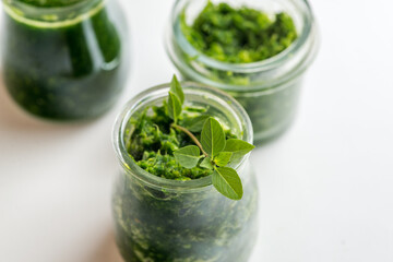 Pesto sauce in three jars on a white background