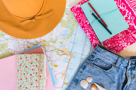 summer hat towel demin shorts notebooks and books laid on map
