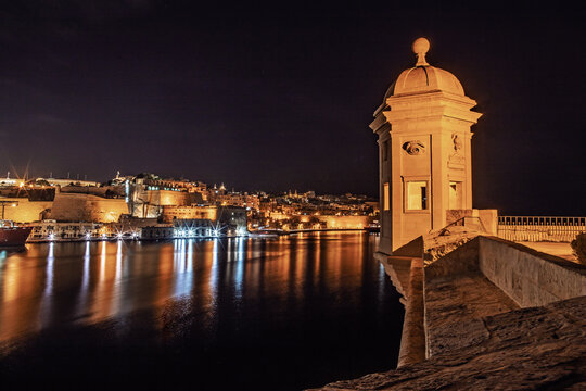 A watchtower stands watch over the harbor of Valleta, Malta at night.