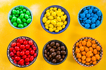 Candy on the yellow background in bowls, colorful candy, multicolored gradient