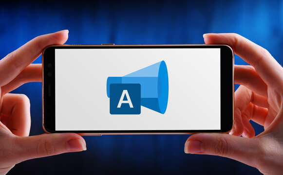 Hands holding smartphone displaying logo of Microsoft Advertisin