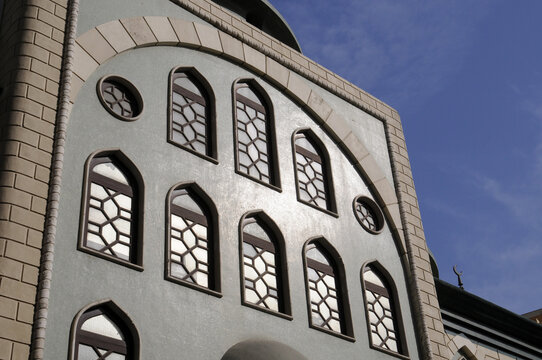 Façade de bâtiment en pierre, de style perse avec une arcade en briques, des fenêtres en vitraux en forme d'ogive et oeil de boeuf. Ancien Dubaï.