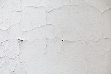 texture of a white old wall with cracks and peeled paint