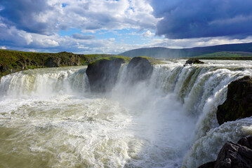 godafoss waterfall, beautiful clouds are in the sky, splashes of water rise into the sky, nature of Iceland