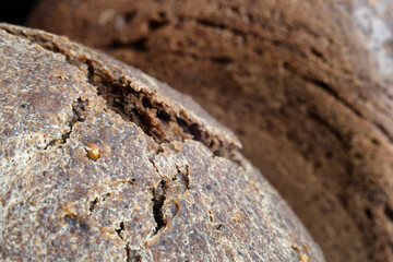 Crust of homemade Borodino bread with coriander and cracks on the background of rye bread
