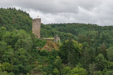 tower of old castle ruin Oberburg on a rocky hill surrounded by green forest, Manderscheid, Germany