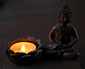 burning candle on a candlestick with a small buddha