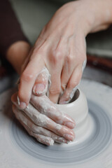 close up hand modeling pottery on a potter wheel in a cozy home workshop. Creating products from environmentally friendly clay with their own hands. Aesthetically beautiful female hands of the artist