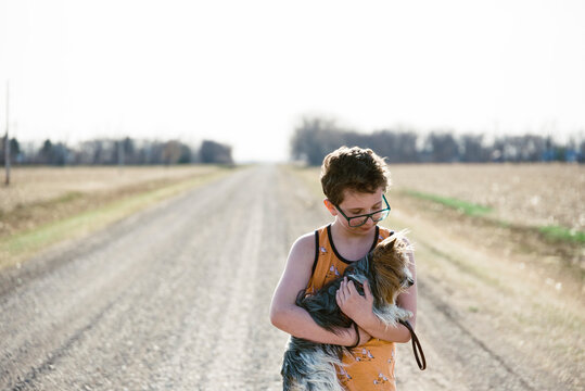 Backlit picture of a boy with his pet Yorkie outdoors.